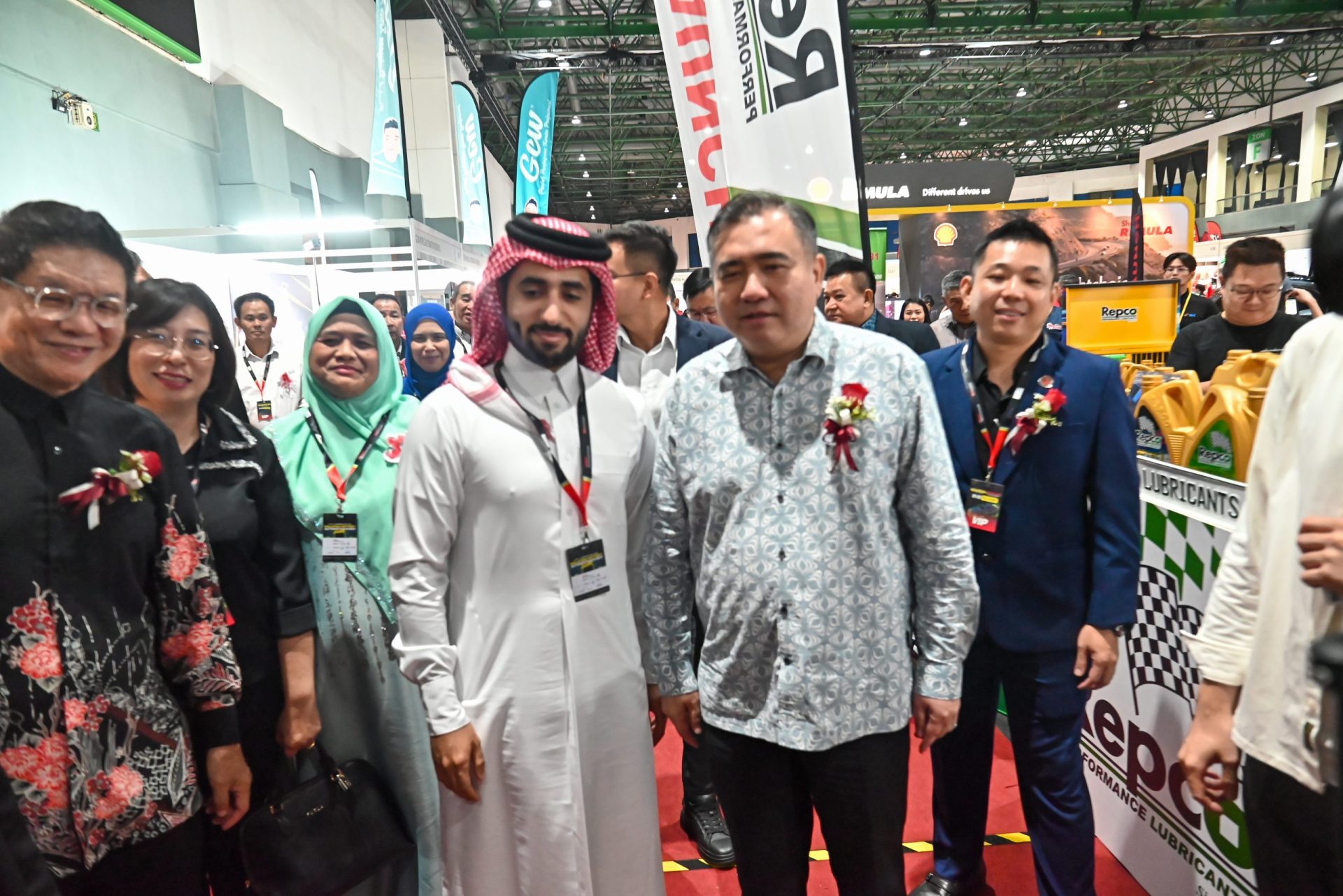 Visitors and exhibitors on the MIAPEX exhibition floor, with automotive parts and lubricant stands in view